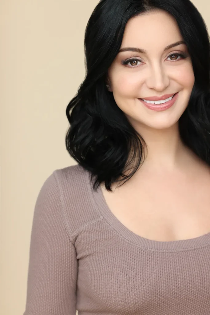 Smiling woman with dark hair, beige background.